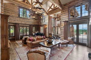 Expansive living area featuring exposed log walls, a vaulted ceiling with exposed wood beams, and wood-finish flooring