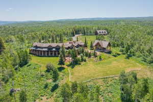 Expansive property featuring multiple structures, including a primary residence with stone and log detailing, a detached outbuilding, and a separate covered pavilion