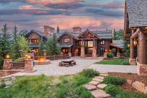 Expansive paver patio featuring a stone fire pit, wood-beam railings, and integrated lighting