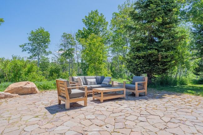 Expansive stone patio featuring irregular flagstone pavers and surrounding mature trees