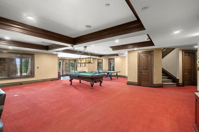 Spacious entertainment area featuring coffered ceilings, recessed lighting, and rich wood trim