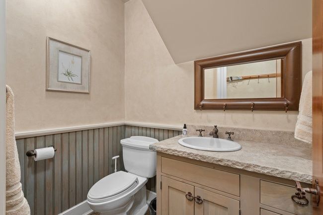 Bathroom featuring beadboard wainscoting, a neutral wall finish, and a stone-look countertop