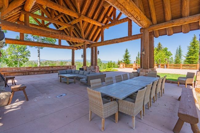 Expansive outdoor covered patio featuring a robust log beam ceiling structure