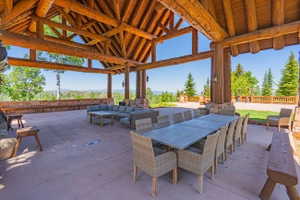 Expansive outdoor covered patio featuring a robust log beam ceiling structure