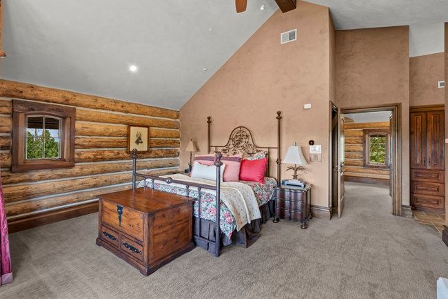 Vaulted ceiling room featuring natural log walls and wood-trimmed windows