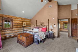 Vaulted ceiling room featuring natural log walls and wood-trimmed windows