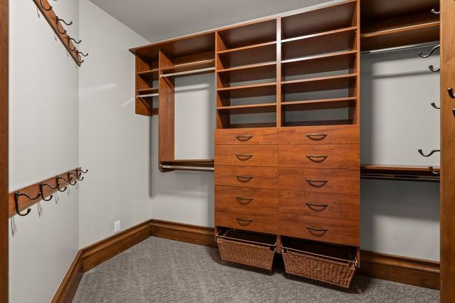 Custom closet system featuring rich wood-finish cabinetry, integrated shelving, multiple hanging rods, and built-in drawers with pulls