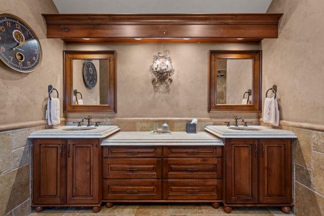 Double vanity featuring rich wood-finish cabinetry, integrated sinks, and light-toned countertops