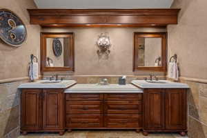 Double vanity featuring rich wood-finish cabinetry, integrated sinks, and light-toned countertops