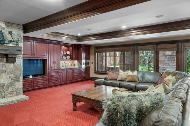 Spacious living area featuring extensive built-in cabinetry, a stone fireplace, and ample natural light through large windows