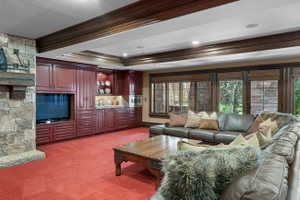 Spacious living area featuring extensive built-in cabinetry, a stone fireplace, and ample natural light through large windows