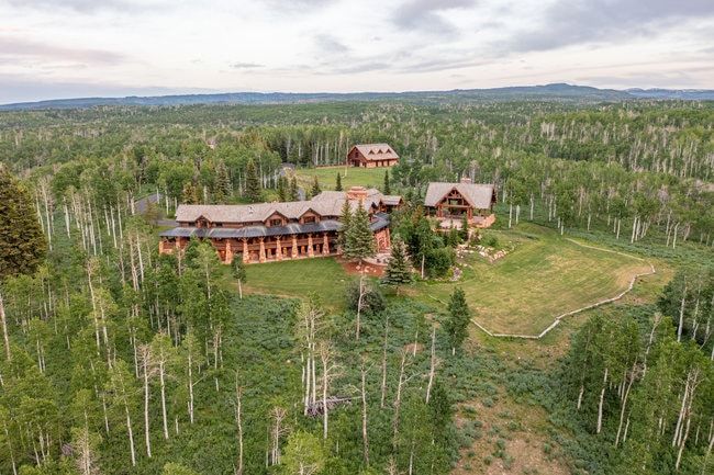 Expansive multi-structure property featuring log cabin construction, gabled roofs, and an established lawn