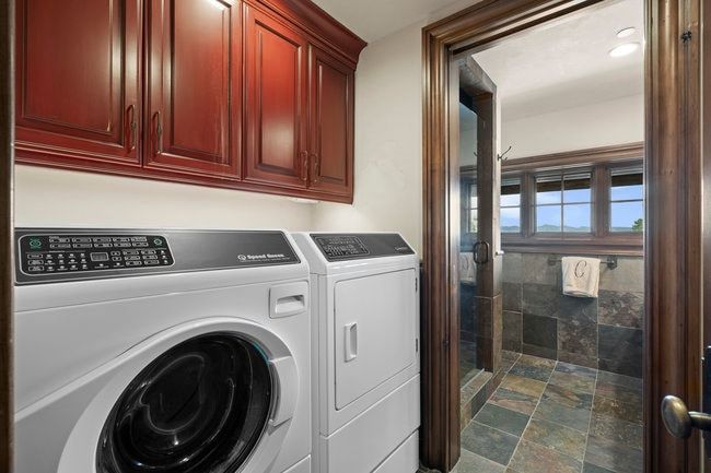 Laundry area featuring rich wood cabinetry, a front-loading washing machine, and a dryer