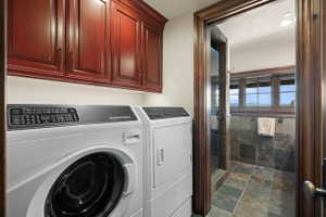 Laundry area featuring rich wood cabinetry, a front-loading washing machine, and a dryer