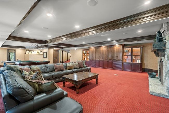 Spacious recreation room featuring recessed lighting, extensive built-in cabinetry, an integrated stone fireplace, and wood-finish ceiling trim