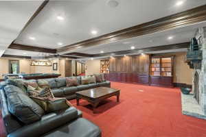 Spacious recreation room featuring recessed lighting, extensive built-in cabinetry, an integrated stone fireplace, and wood-finish ceiling trim