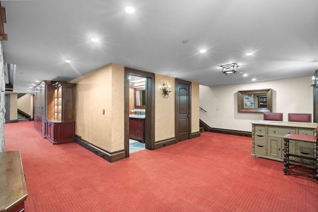 Spacious room featuring red patterned carpeting, recessed lighting, and dark wood-stained trim