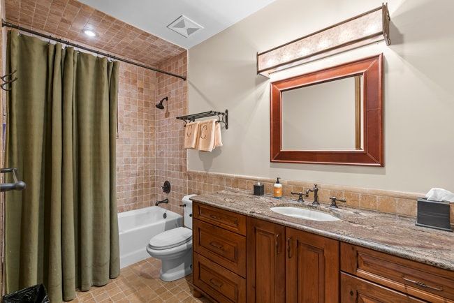 Bathroom featuring a wood-finish vanity with an integrated sink and a stone countertop