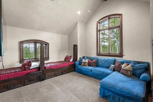 Vaulted ceiling room featuring a large arched wood-frame window, two built-in wood-finish beds with storage drawers, and recessed lighting