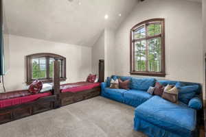 Vaulted ceiling room featuring a large arched wood-frame window, two built-in wood-finish beds with storage drawers, and recessed lighting