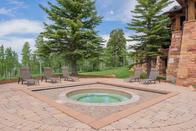 Outdoor spa with integrated cover, surrounded by a paver patio with a contrasting border