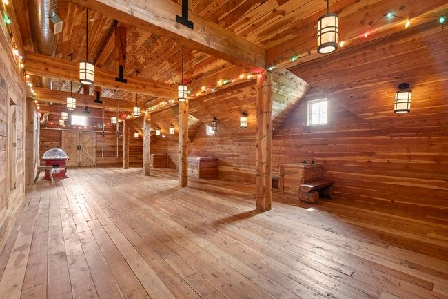Spacious room featuring extensive wood-finish flooring, exposed wood beams, and sloped wood-paneled ceilings