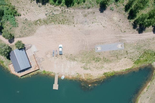 Waterfront property featuring a private dock, boat ramp, and a structure with a dark roof and surrounding wood decking