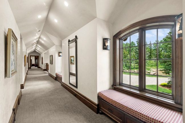Hallway featuring an arched window, a built-in window seat with storage, decorative wall sconces, recessed lighting, and wood-finish trim