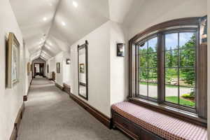 Hallway featuring an arched window, a built-in window seat with storage, decorative wall sconces, recessed lighting, and wood-finish trim