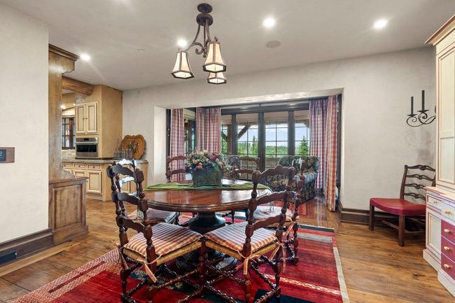 Dining area featuring wood-finish flooring, a decorative chandelier, recessed lighting, and a partial view of a kitchen with light-toned cabinetry and built-in appliances