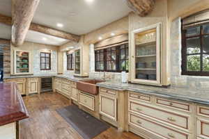 Kitchen featuring wood-finish flooring, exposed wood beams, and stone accent walls
