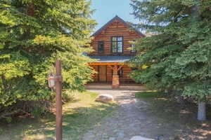 Log cabin style exterior featuring a covered porch, stone column accents, and a dark shingle roof