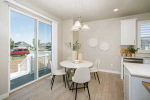 Dining area with light wood-finish flooring, featuring a glass sliding door leading to an outdoor deck