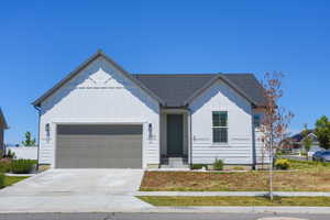 Contemporary ranch-style home featuring white vertical and horizontal siding, a dark gray asphalt shingle roof, and a two-car garage with a paneled door