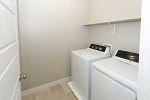 Dedicated laundry space with light-toned walls and wood-finish flooring