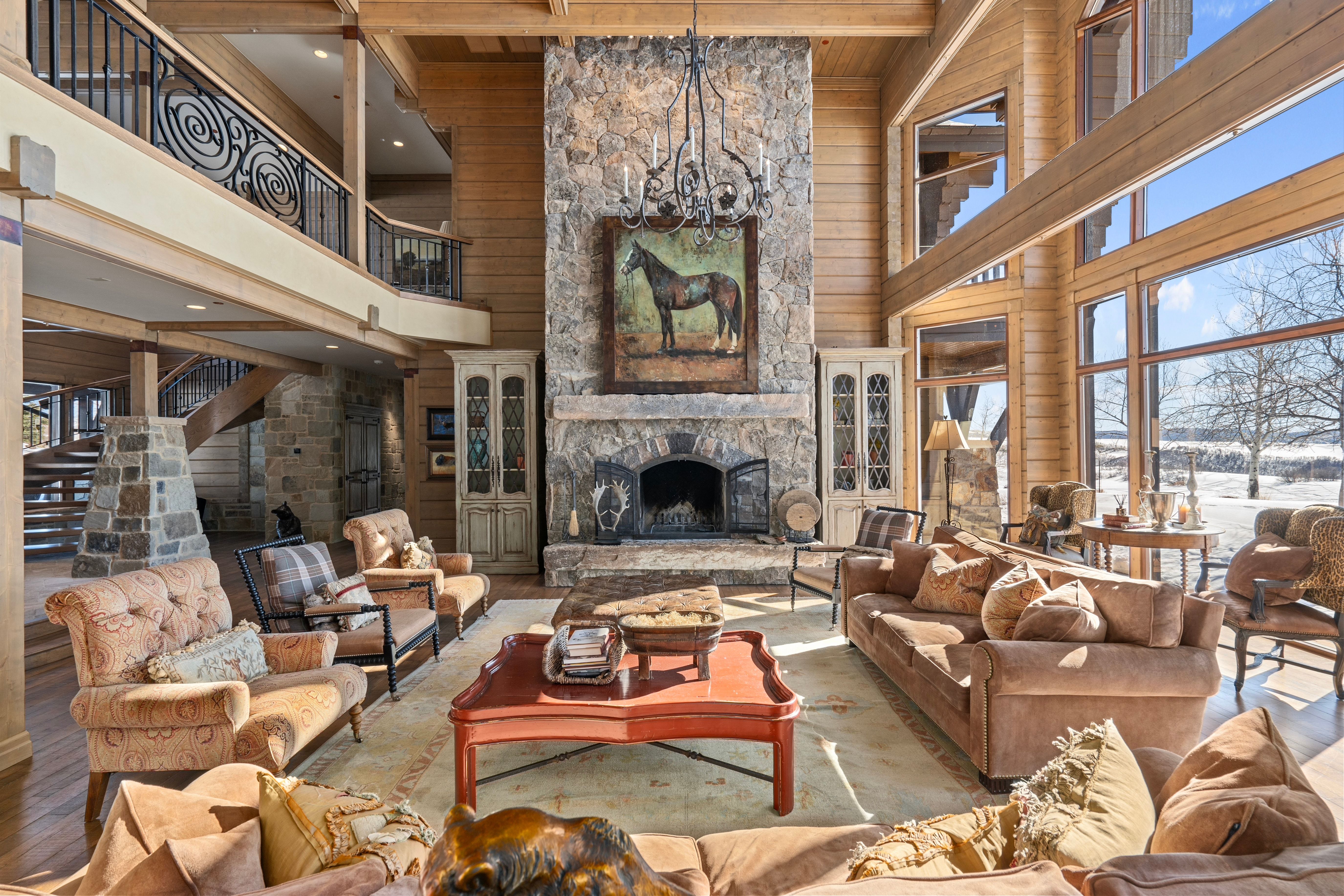 Great room featuring a floor-to-ceiling stone fireplace, high beamed ceilings, and expansive windows