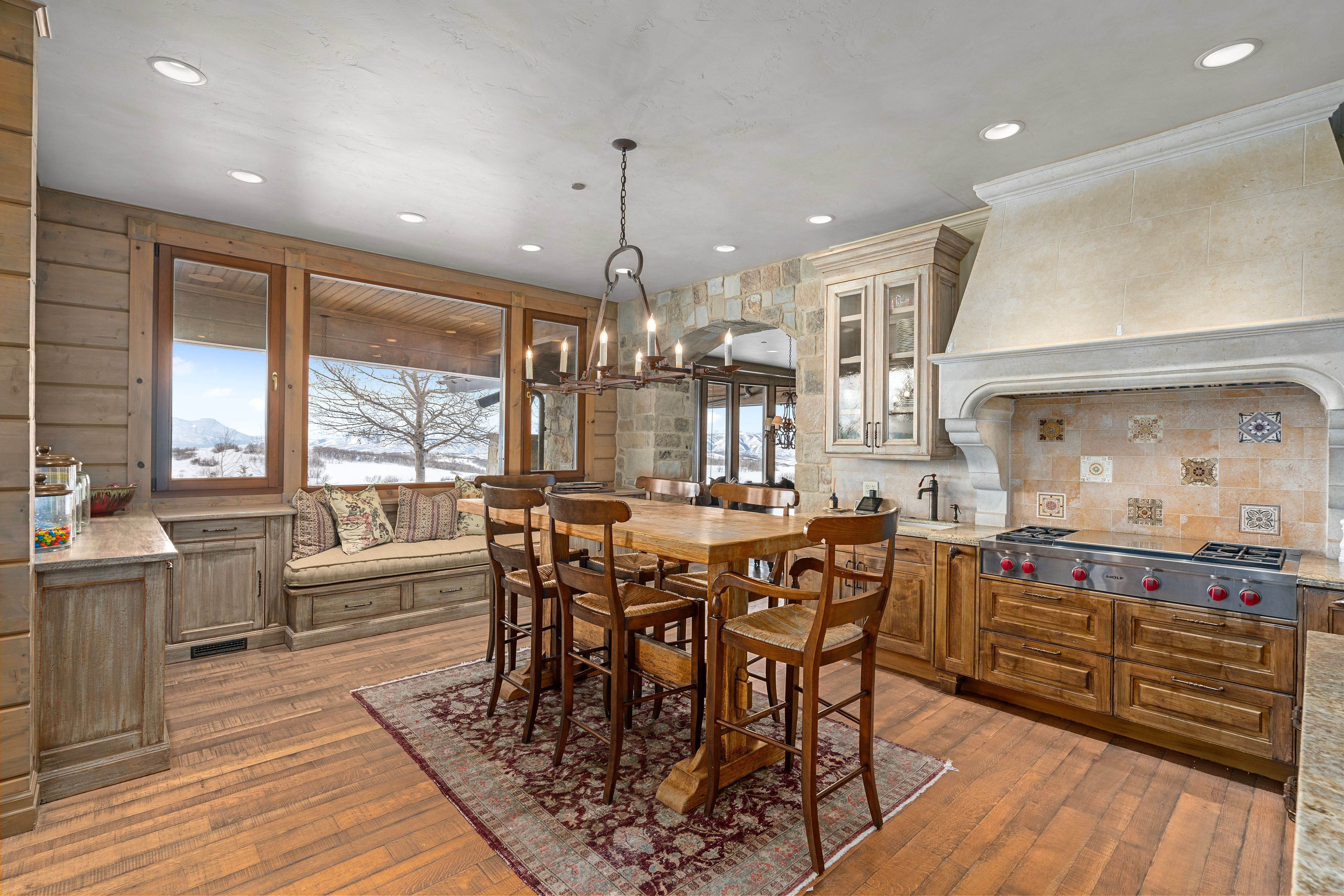 Gourmet kitchen featuring a professional-grade range, custom range hood, stone backsplash, wood-finish cabinetry, and recessed lighting