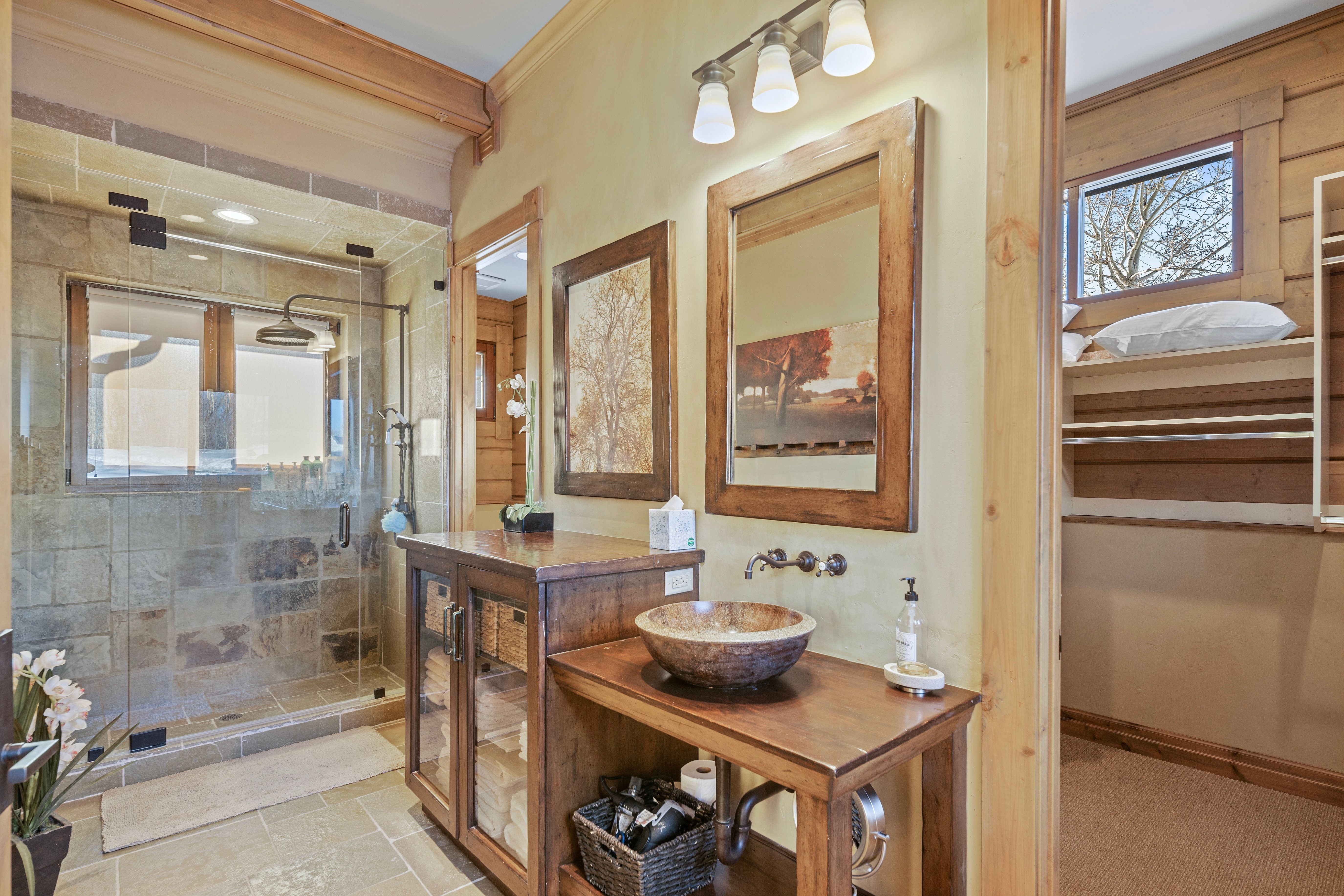 Stone-tiled walk-in shower with glass enclosure and rain shower head