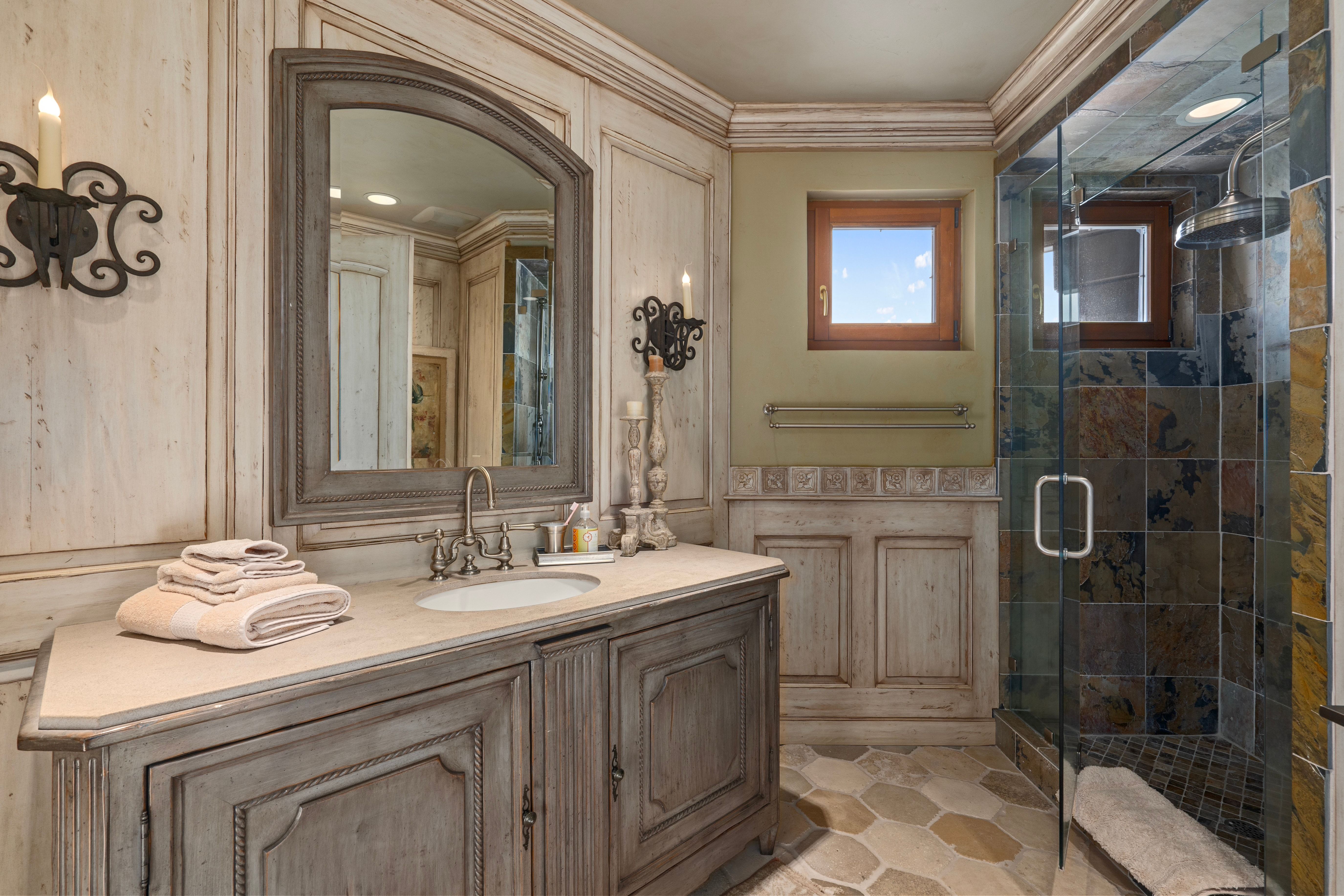 Bathroom featuring a built-in vanity with a countertop sink, a framed mirror, and a glass-enclosed shower with tile surround