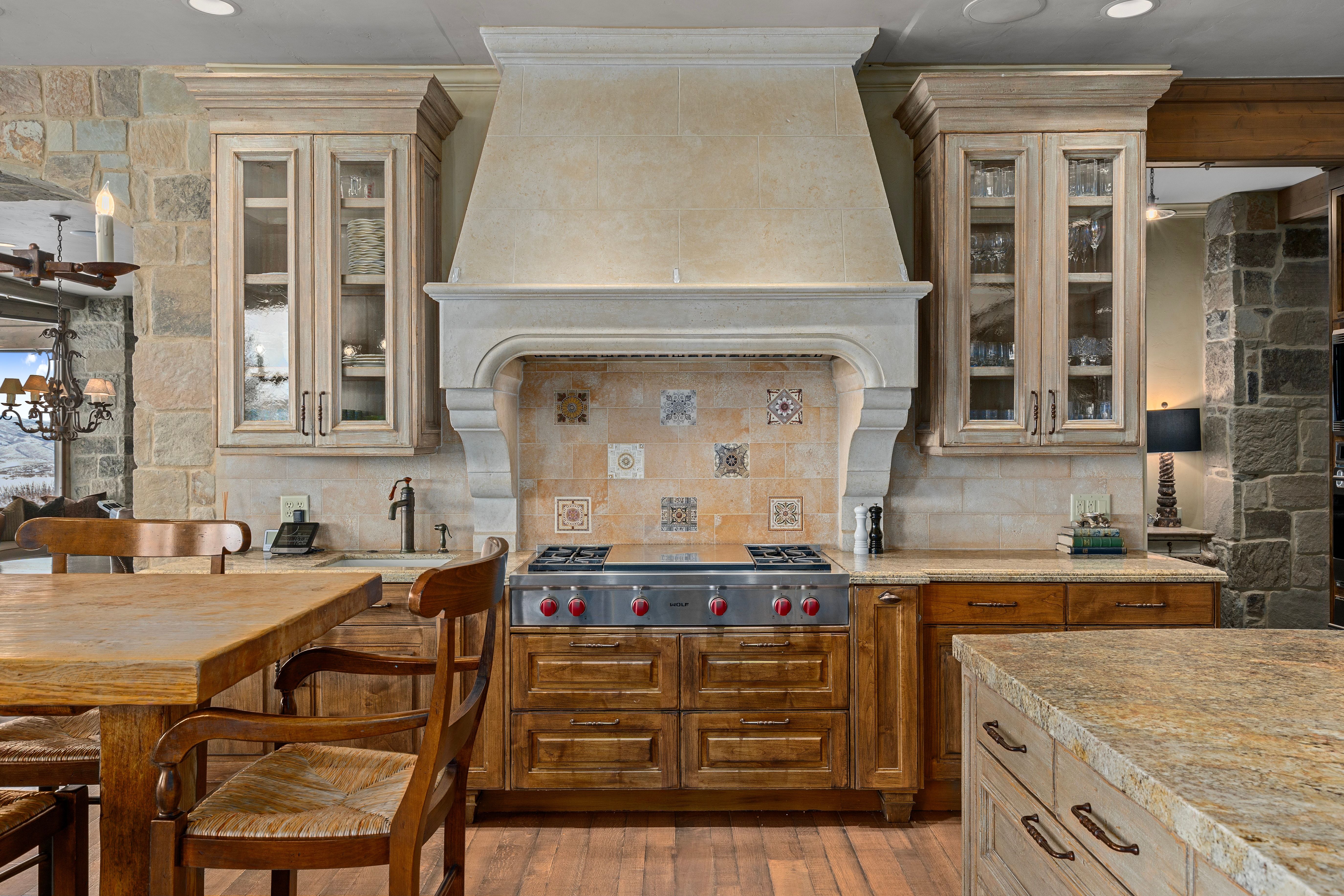 Gourmet kitchen featuring a substantial range hood, a professional-grade gas range, and a tiled backsplash with decorative accents