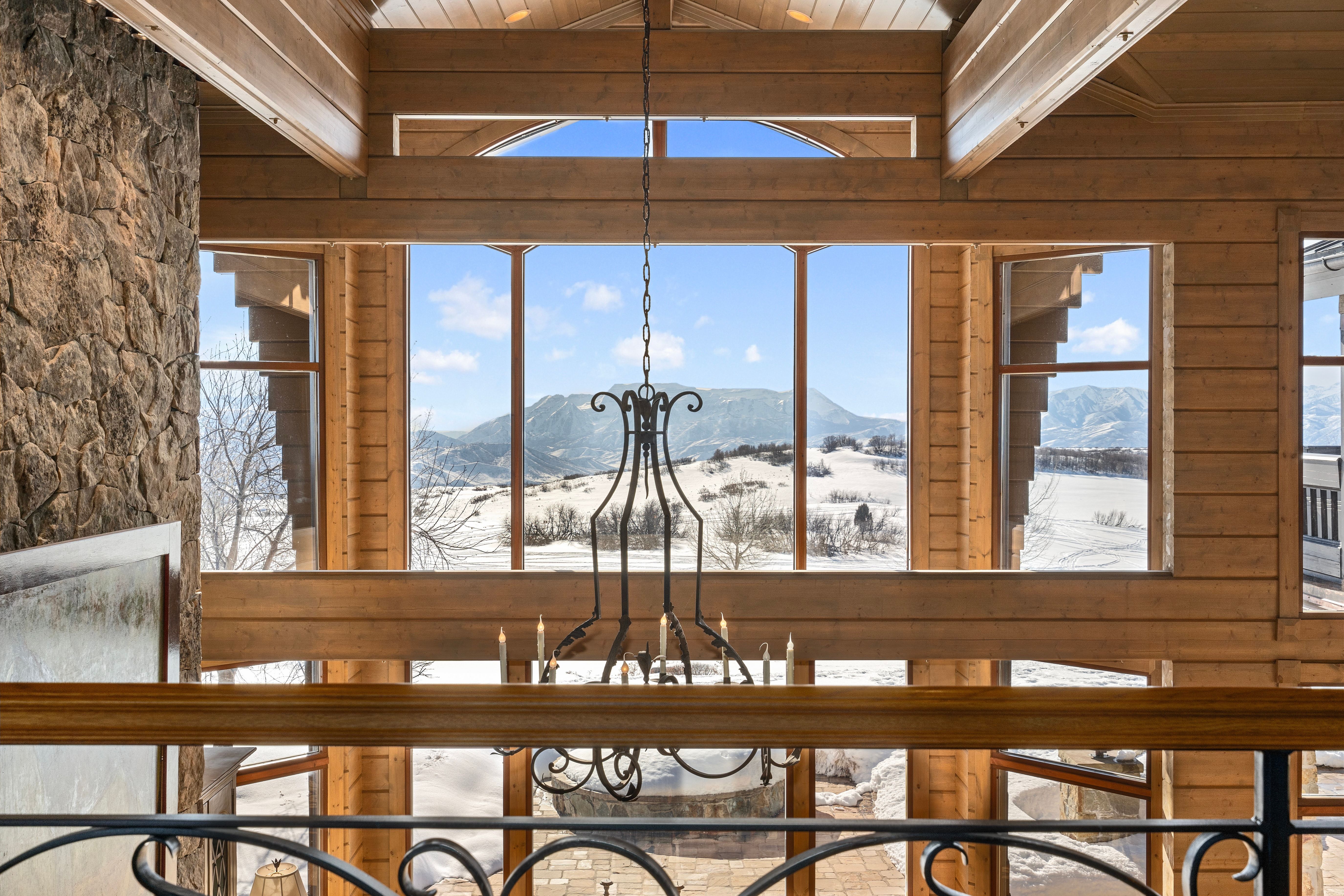Two-story wall of windows framing a snow-covered mountain landscape