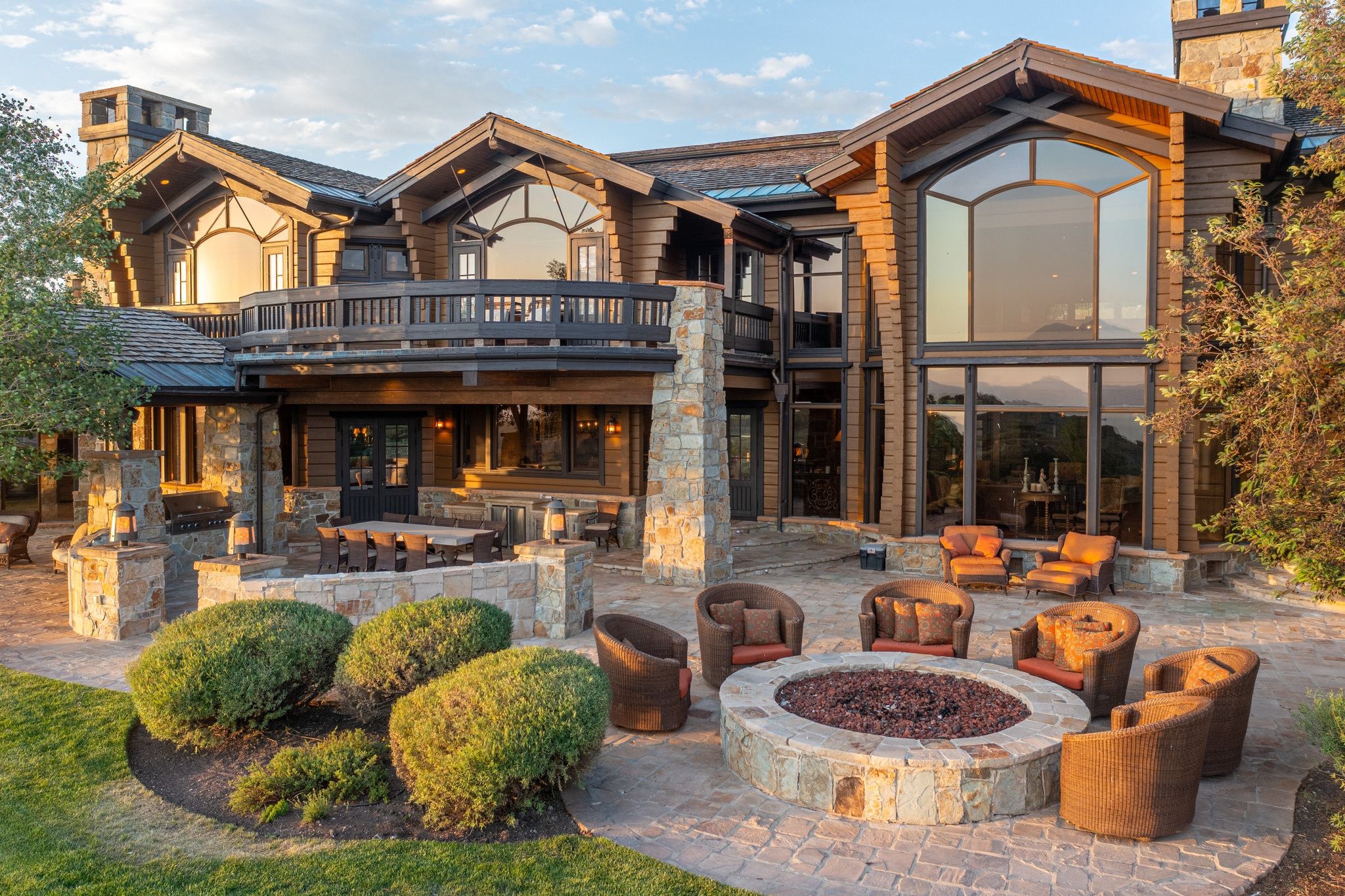 Expansive stone paver patio featuring a built-in stone fire pit, generous outdoor living space, and an additional covered dining area