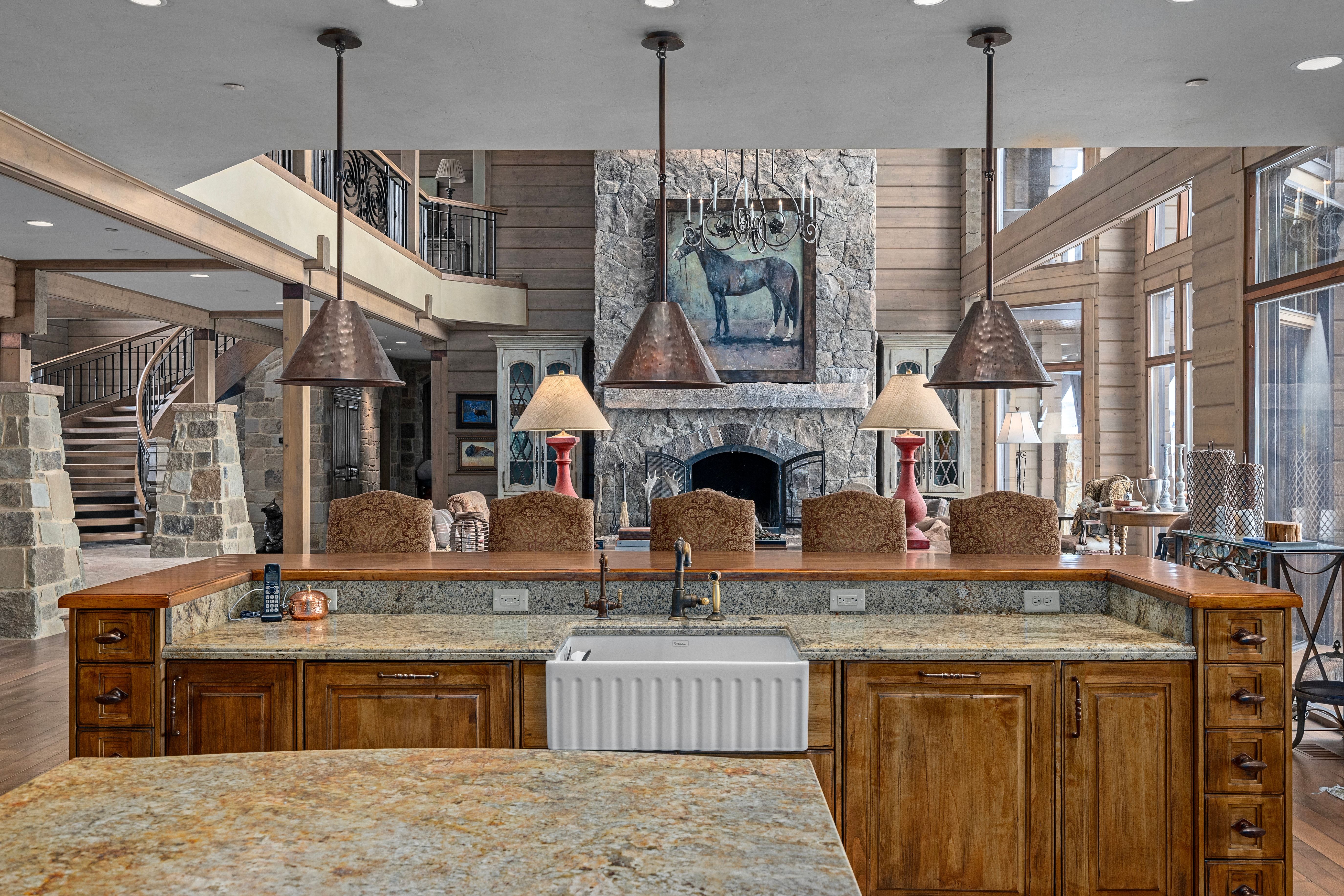 Expansive kitchen island featuring a farmhouse sink, stone countertops, and wood-finish cabinetry