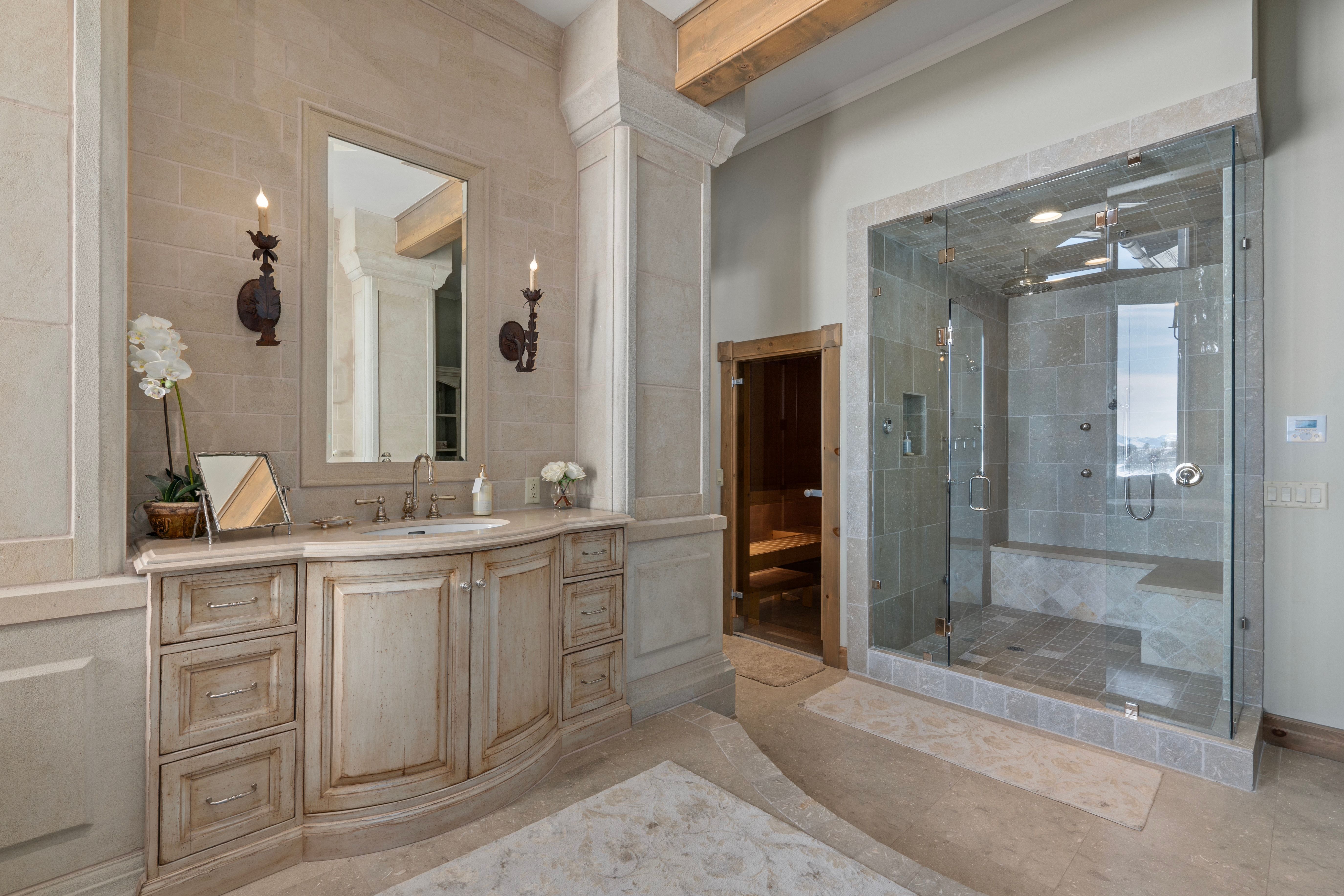 Spacious bath featuring a light wood vanity with an undermount sink, a large framed mirror, and two wall-mounted sconces
