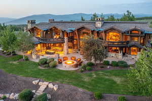 Wood-sided estate featuring multiple balconies, stone chimneys, and expansive windows