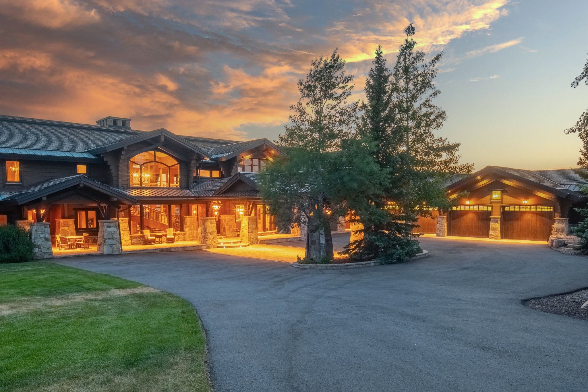 Expansive asphalt driveway leading to a multi-car garage and a grand entryway