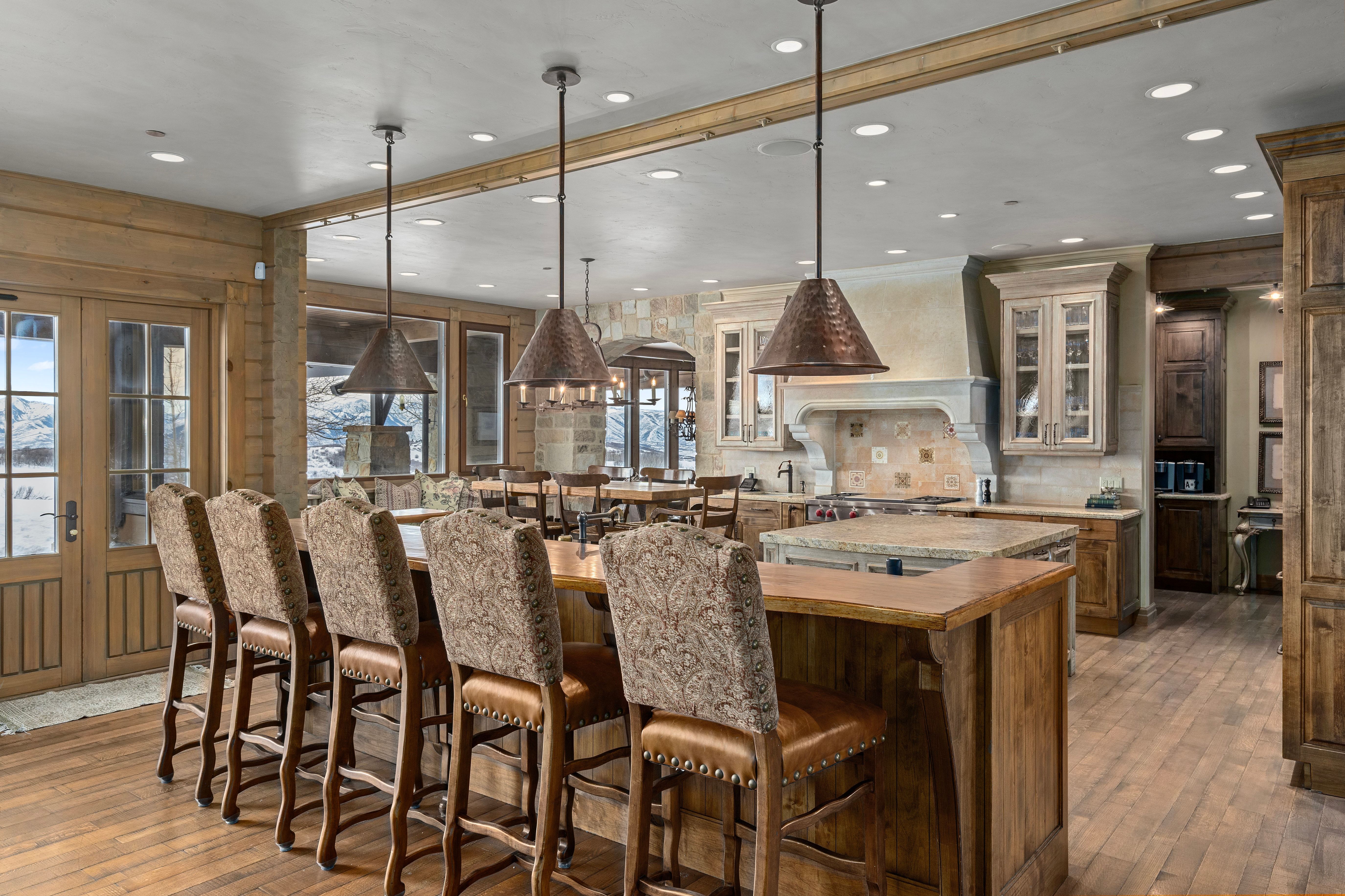 Spacious kitchen featuring a large wood-finish island with seating, pendant lighting, stone countertops, and wood-finish flooring