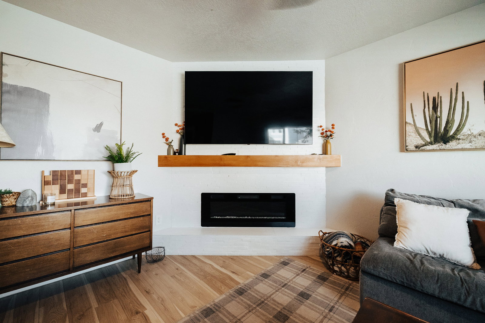Living area featuring an integrated wall-mounted electric fireplace, a substantial wood mantel, and wood-finish flooring