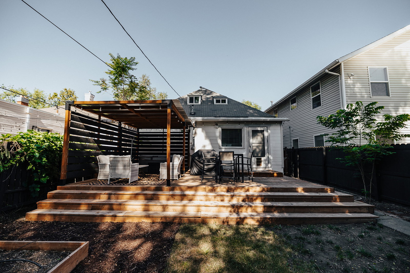 Multi-level wooden deck featuring a built-in pergola with privacy screens, a direct entry to the property, and a wood-framed garden bed