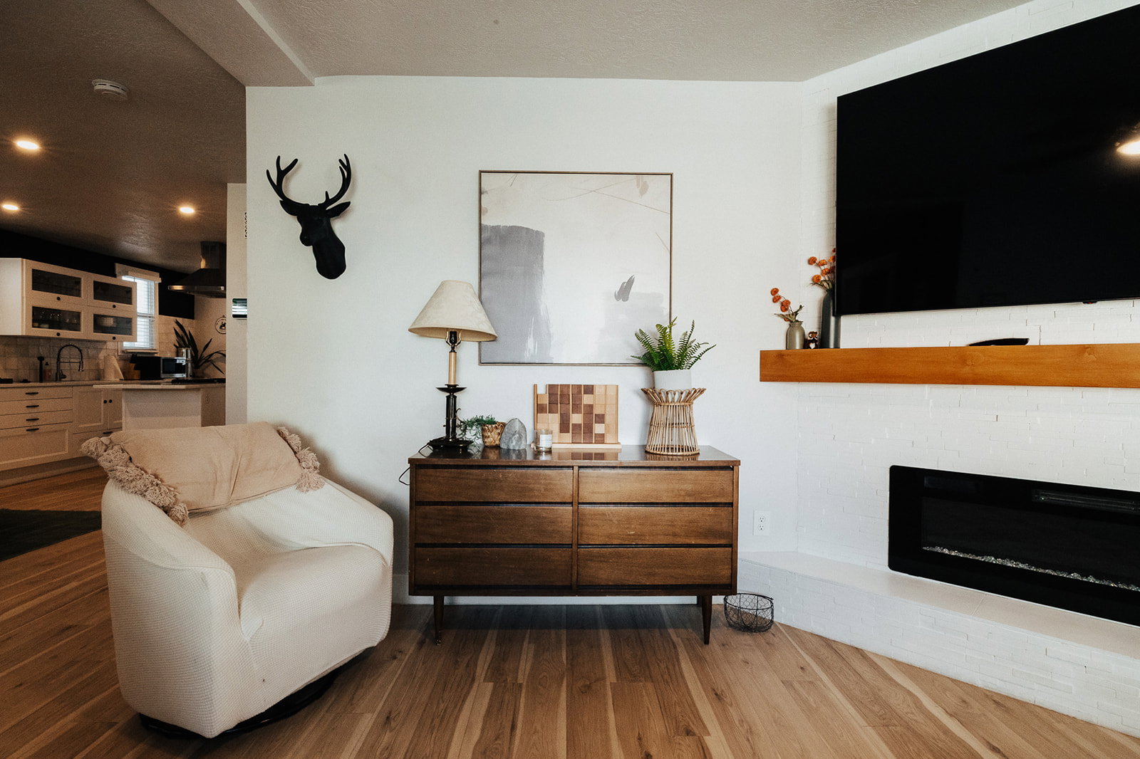 Living area with wood-finish flooring, a white brick fireplace with a wood mantle, and an electric insert